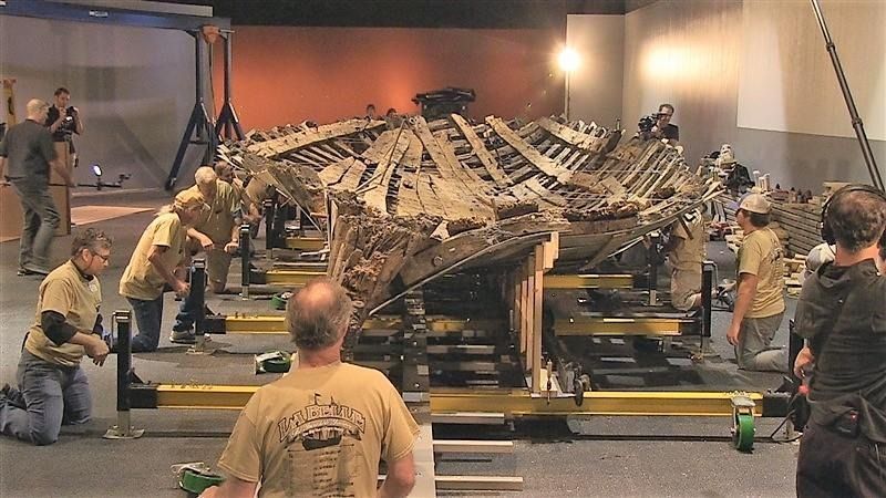 A group of people are working on a large piece of wood