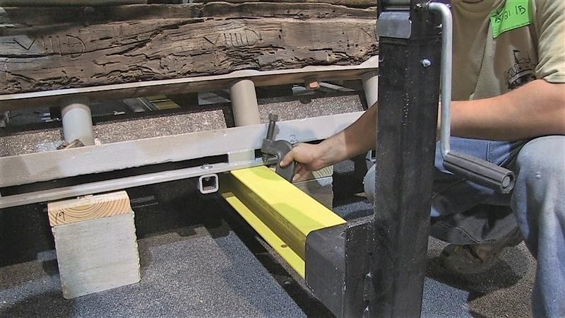 A man is using a forklift to lift a yellow piece of wood.