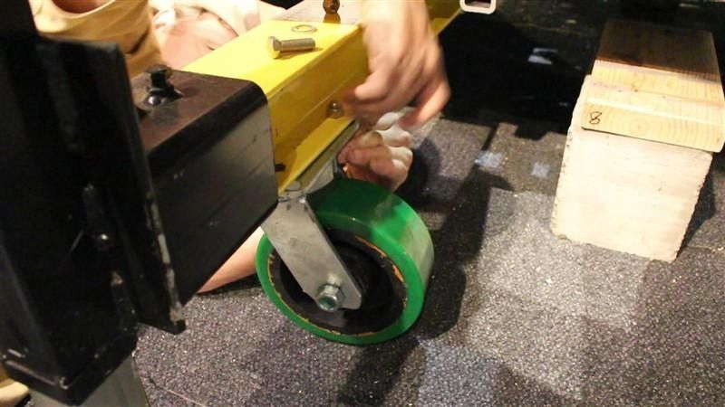 A person is holding a green wheel on a machine.