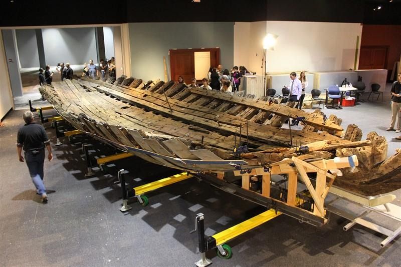 A large wooden boat is on display in a museum