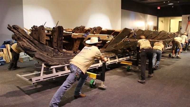 A group of people are working on a large piece of wood.