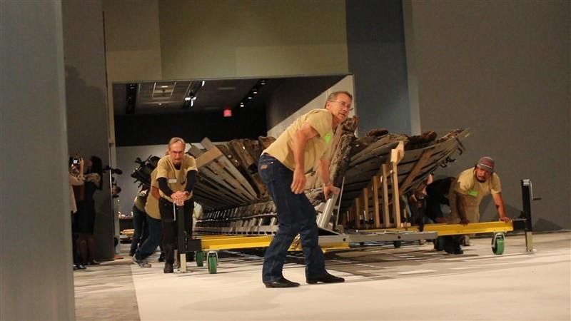A group of people are working on a large piece of wood.