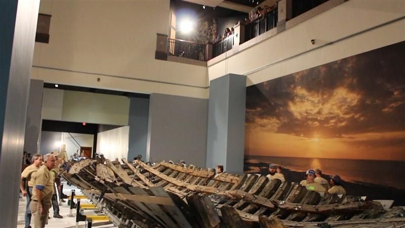 A group of people are standing around a large skeleton in a museum.