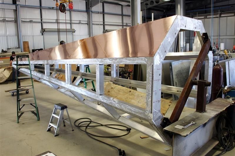 A large metal structure is being built in a factory