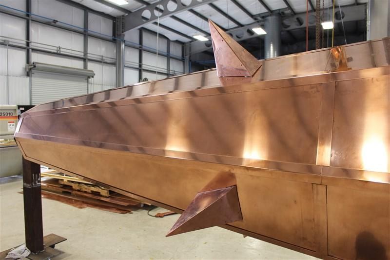 A copper boat is being built in a factory.