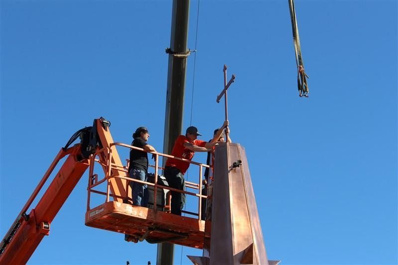 A crane is lifting a cross into the air