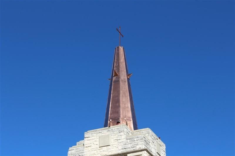 A church steeple with a cross on top of it against a blue sky.
