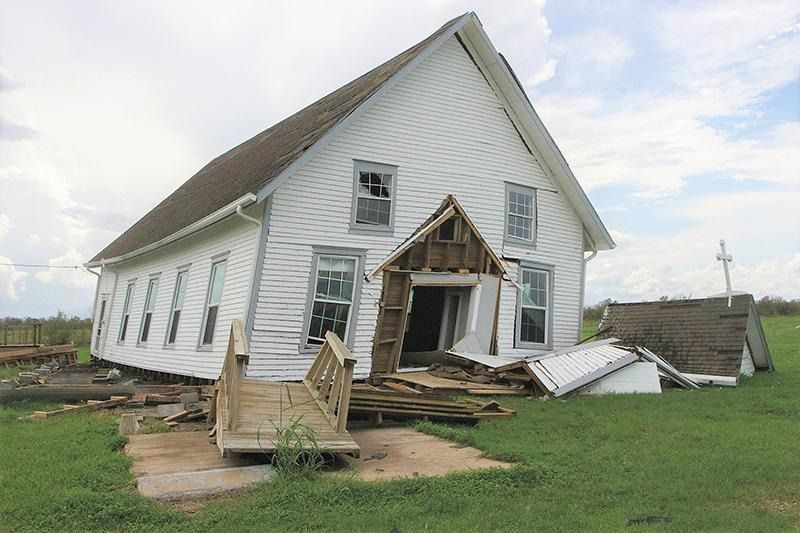 A white house is sitting on its side in a grassy field.