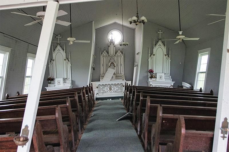 The inside of a church with wooden pews and ceiling fans
