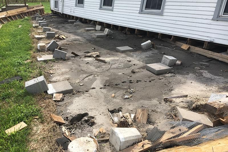 A white house with a lot of bricks on the ground in front of it.