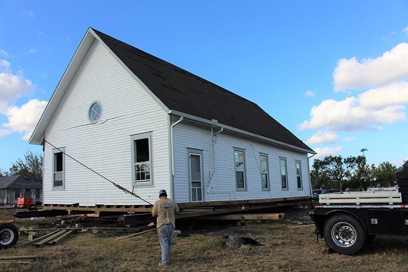 A large white house is being moved by a truck