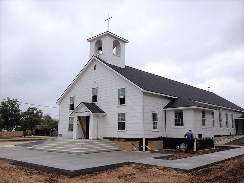 A white church with a black roof and a cross on top