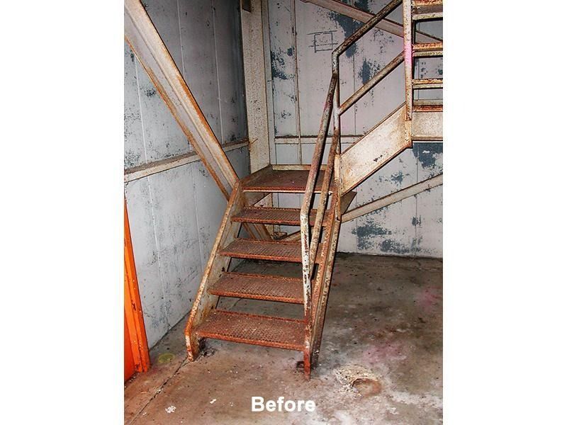 A picture of a rusty metal staircase in a building before being remodeled.