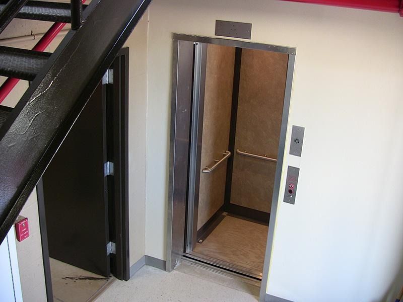 An elevator with the door open and a staircase in the background