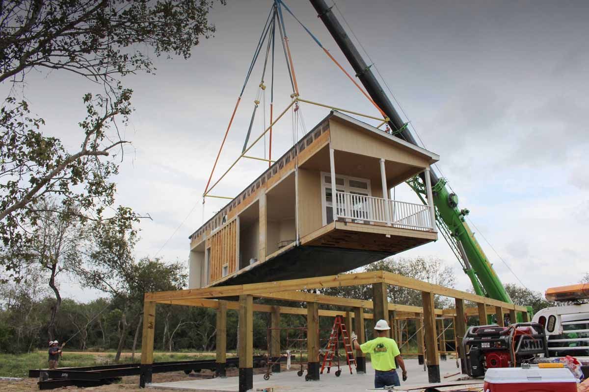 A crane is lifting a house into place.