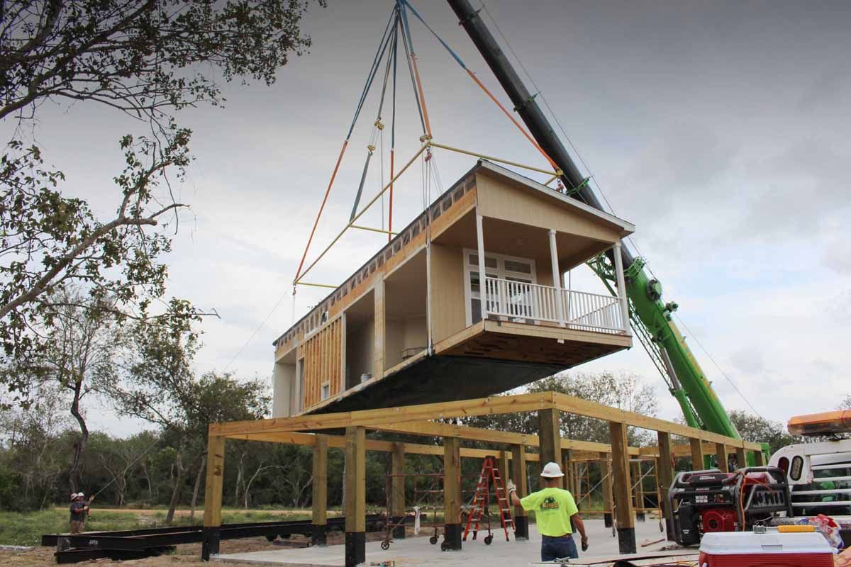A crane is lifting a house into place.