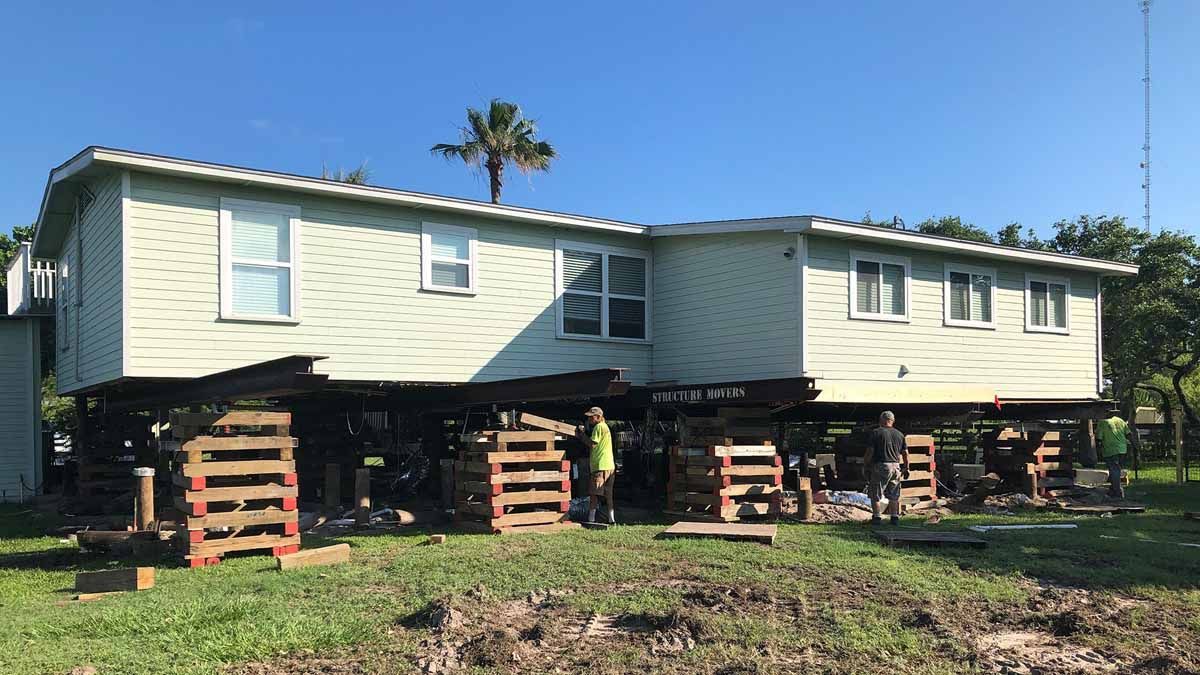 A house is being moved to a new location on stilts.