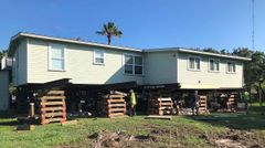 A house is being moved to a new location on stilts.