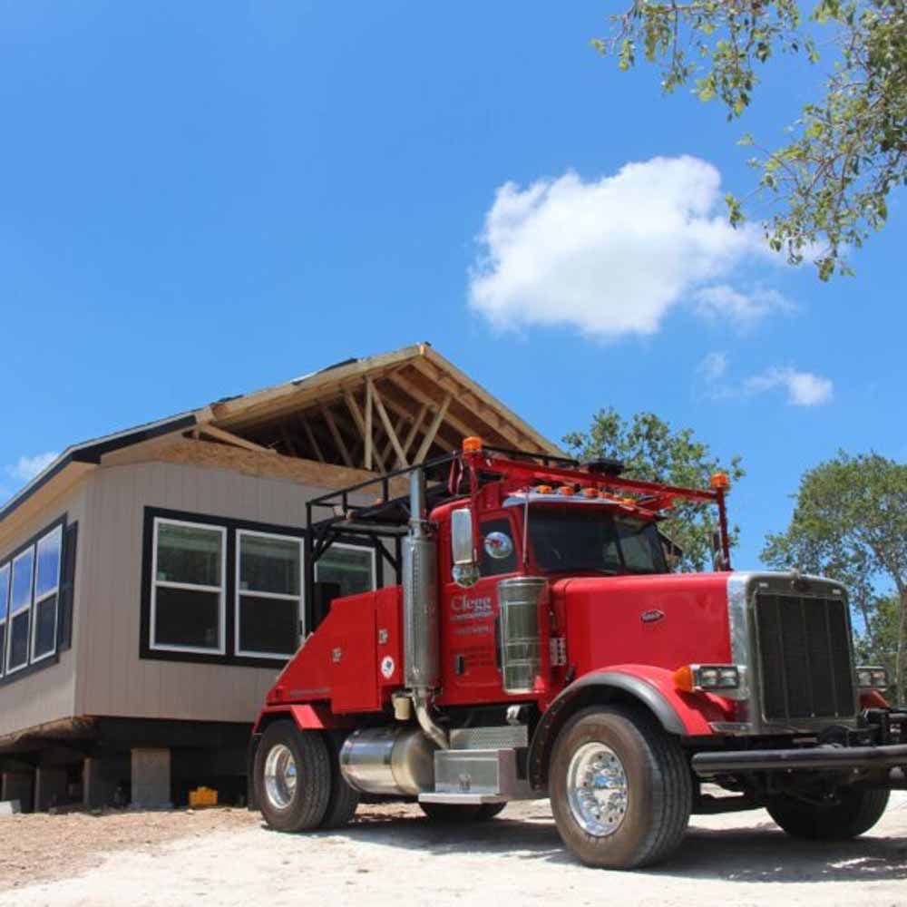 A red truck is parked in front of a house under construction
