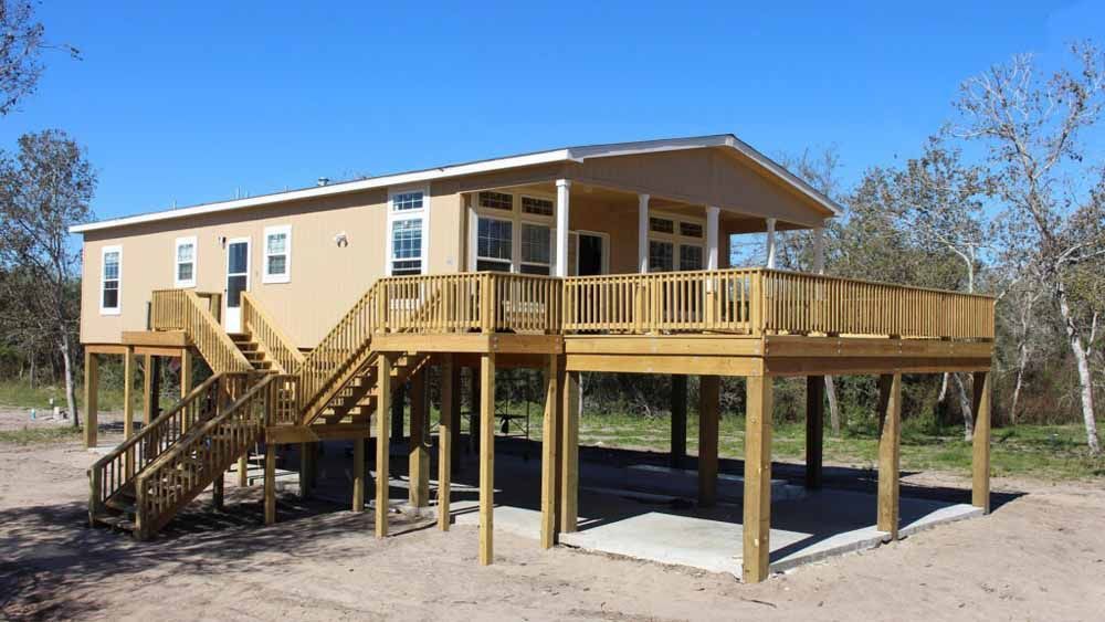 A house on stilts with a large deck and stairs