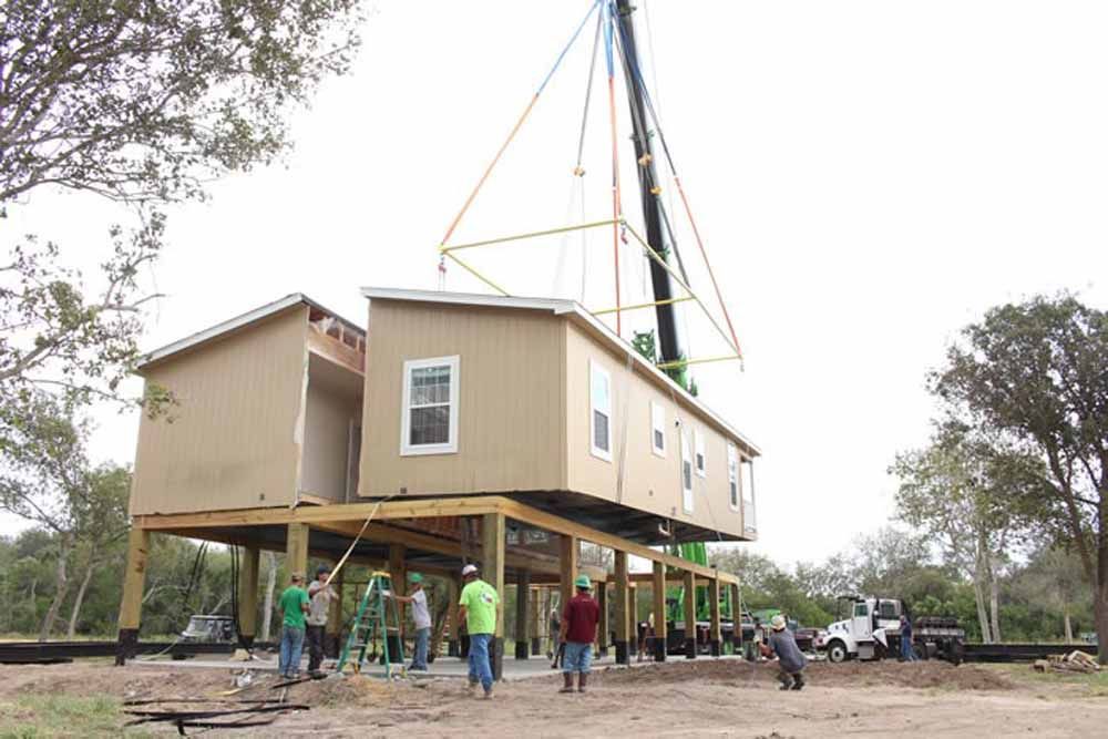 A crane is lifting a house into place.