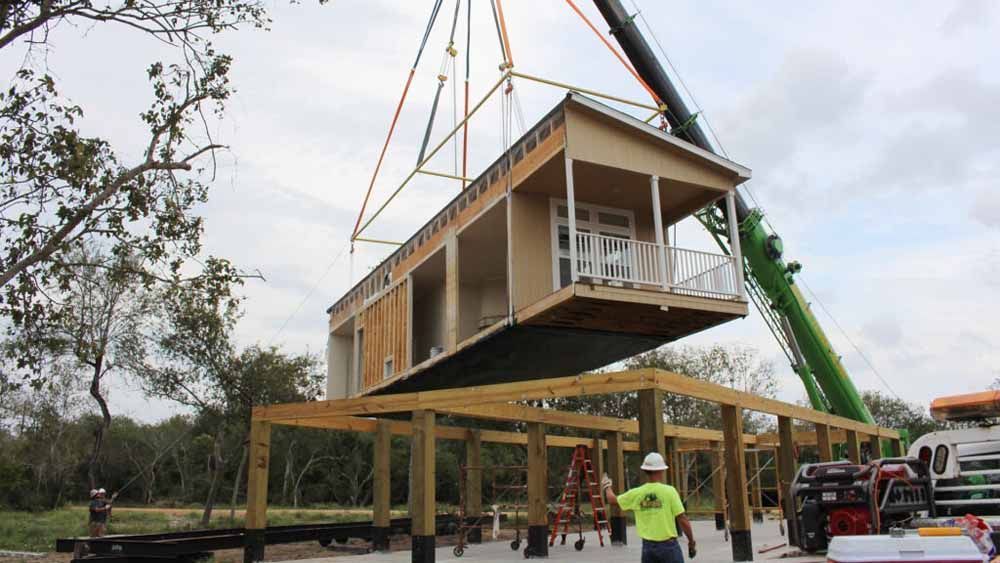 A crane is lifting a house into the air.