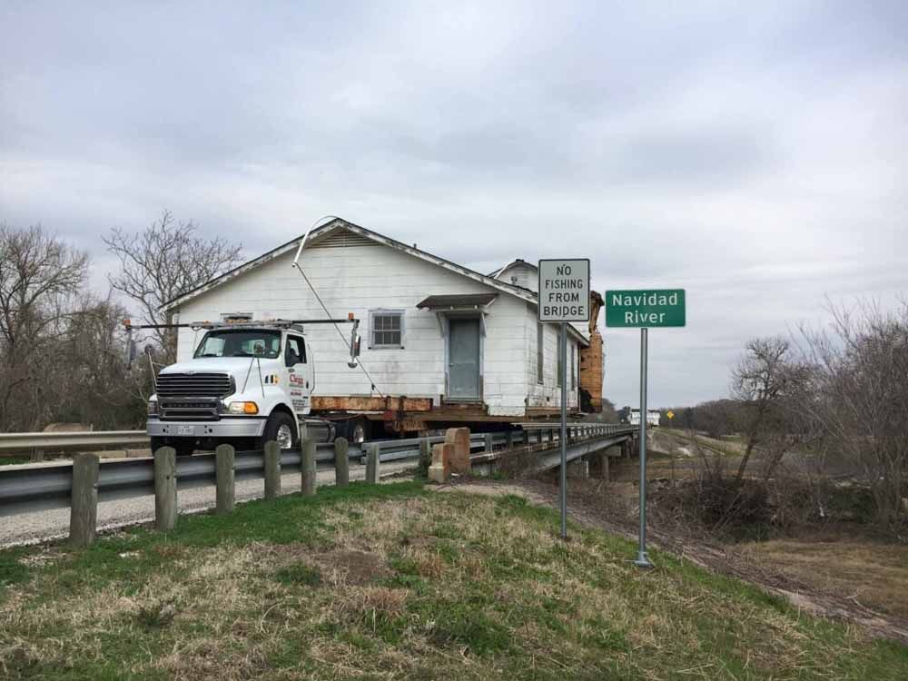 A truck is carrying a house across a bridge.