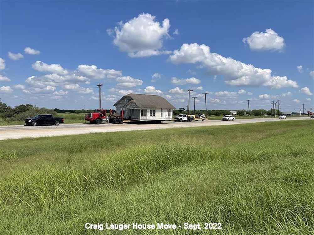 A house is being moved down the road on a trailer.