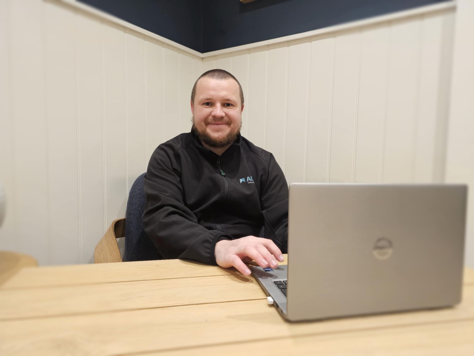 A man wearing glasses is sitting at a table using a laptop computer.
