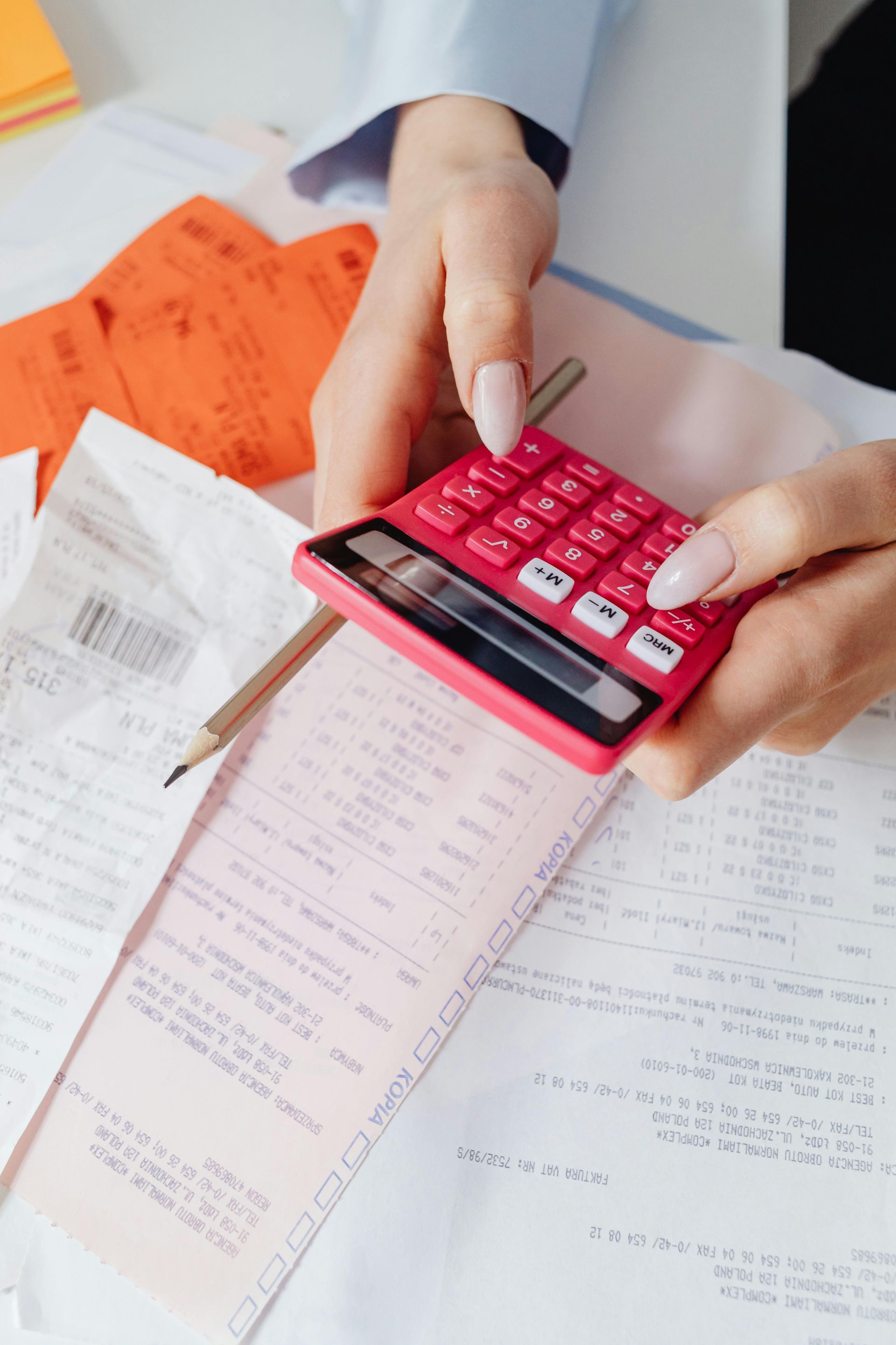 A woman is holding a red calculator over a receipt.