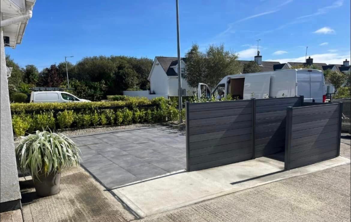 A driveway with a fence and a white van parked in front of a house.