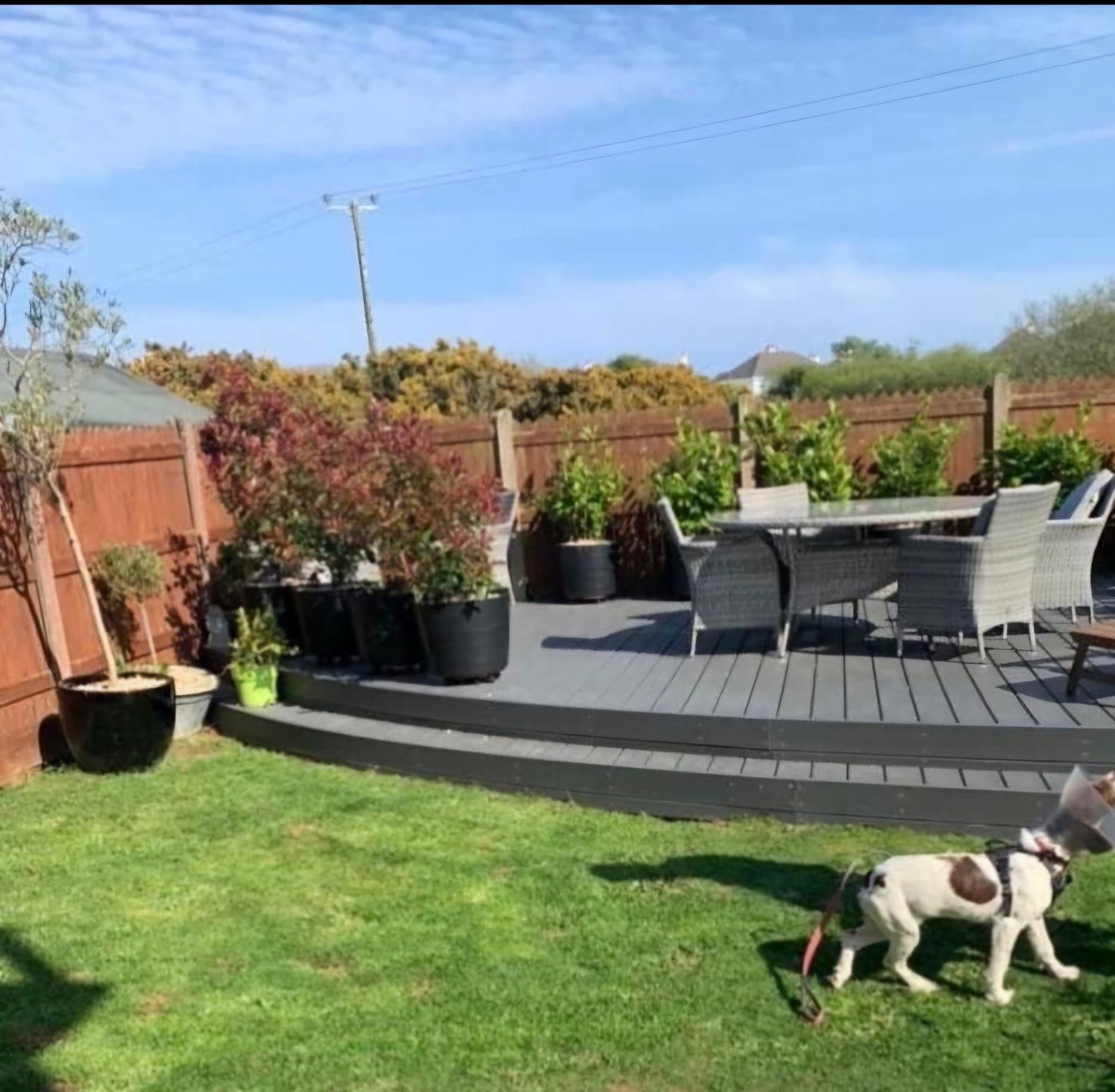 A white house with solar panels on the roof is surrounded by gravel and trees.