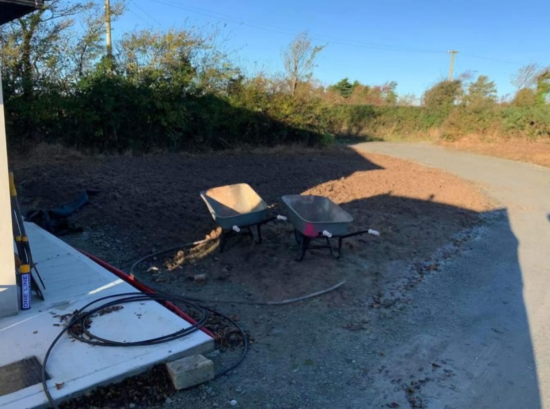 A chair and a wheelbarrow are sitting on the side of a road.