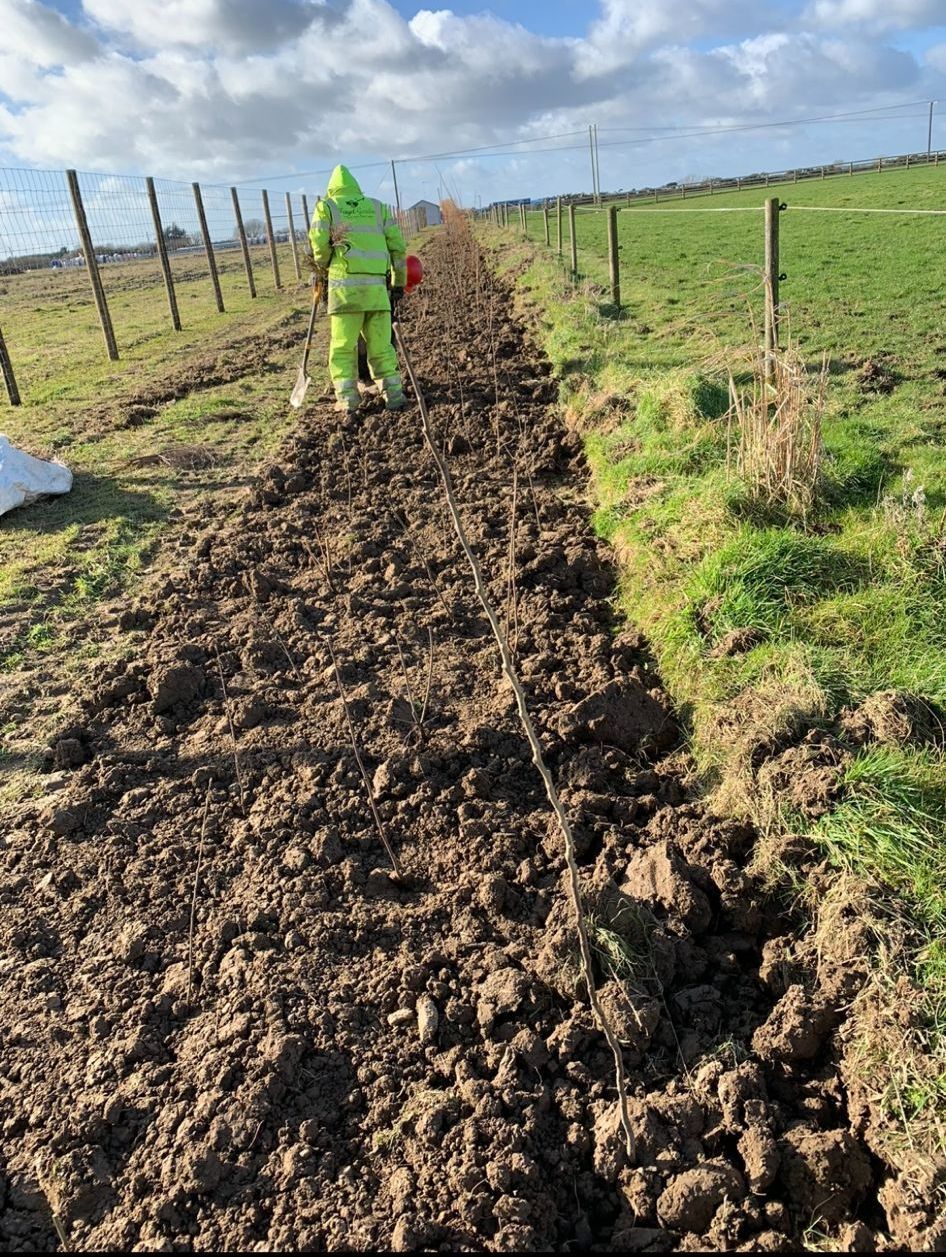 A man in a green suit is walking through a muddy field.