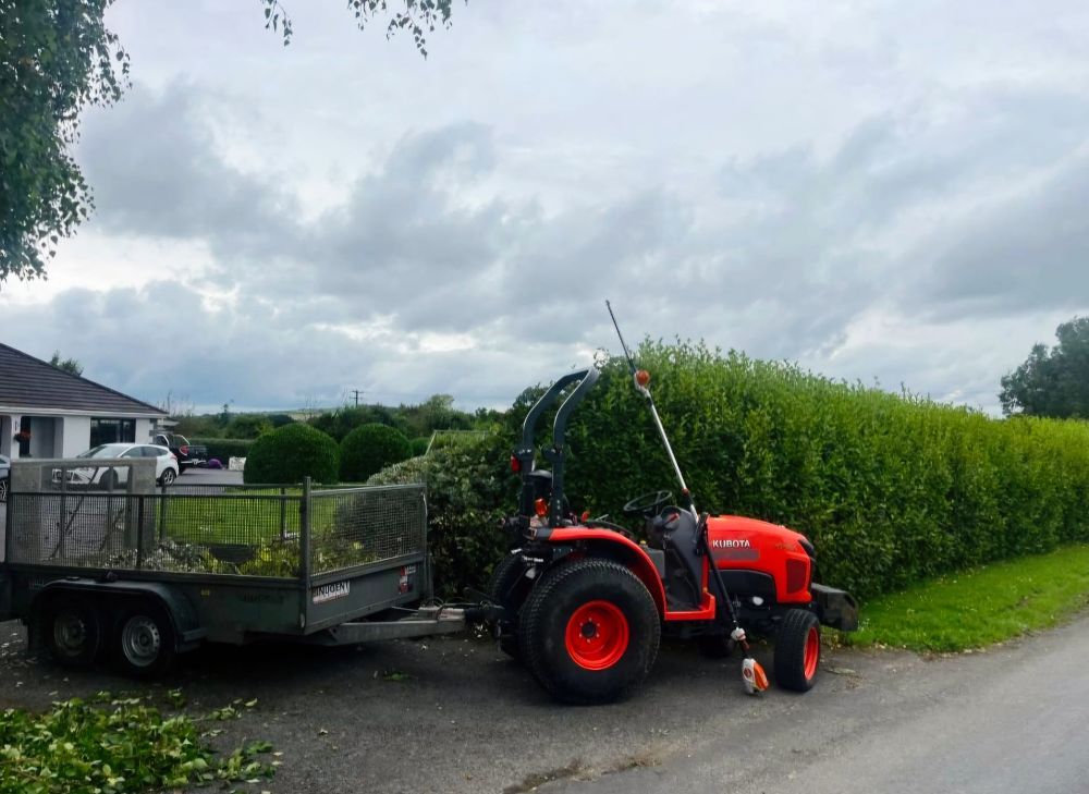 A red tractor with a trailer attached to it is parked on the side of the road.
