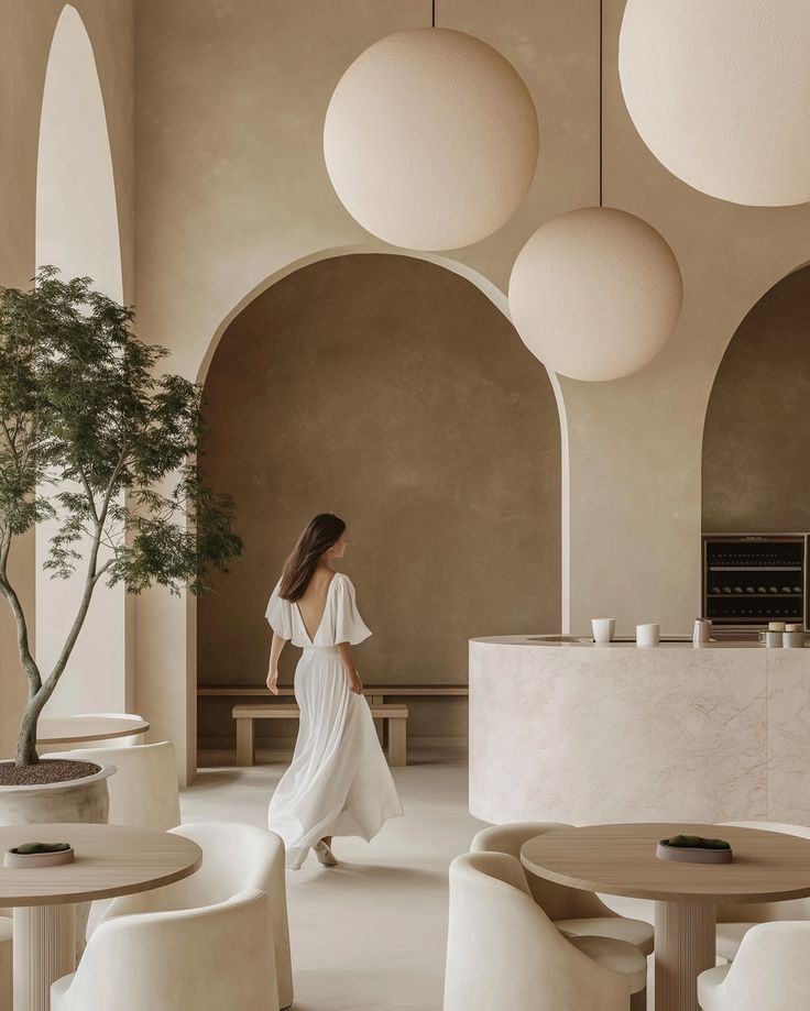 A woman in a white dress is walking through a room with tables and chairs.