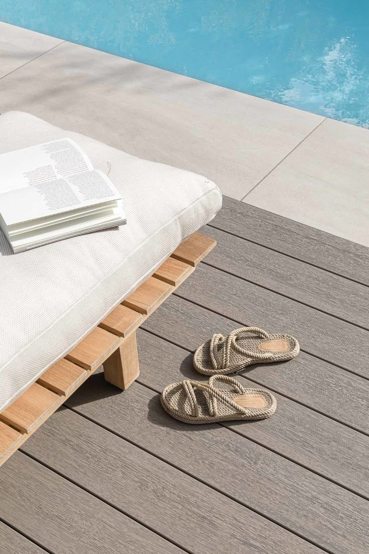A pair of sandals are sitting on a wooden deck next to a pool.
