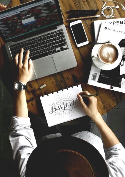 A person is sitting at a table with a laptop and a cup of coffee.