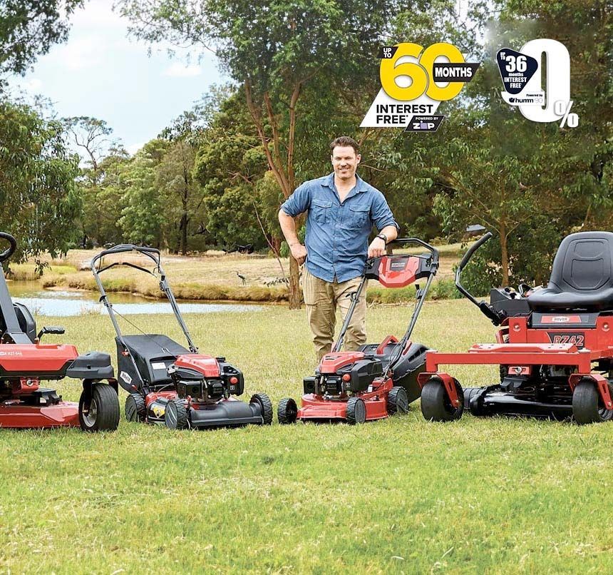 A Man Standing Next to Three Lawn Mowers in a Grassy Field — Jacksons Mower Centre in Mackay, QLD