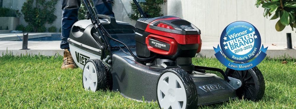 A Person is Using a Lawn Mower on a Lush Green Lawn — Jacksons Mower Centre in Mackay, QLD