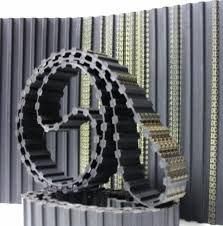 Cinghie di trasmissione dentate nere avvolte con varie cinghie dritte sullo sfondo.