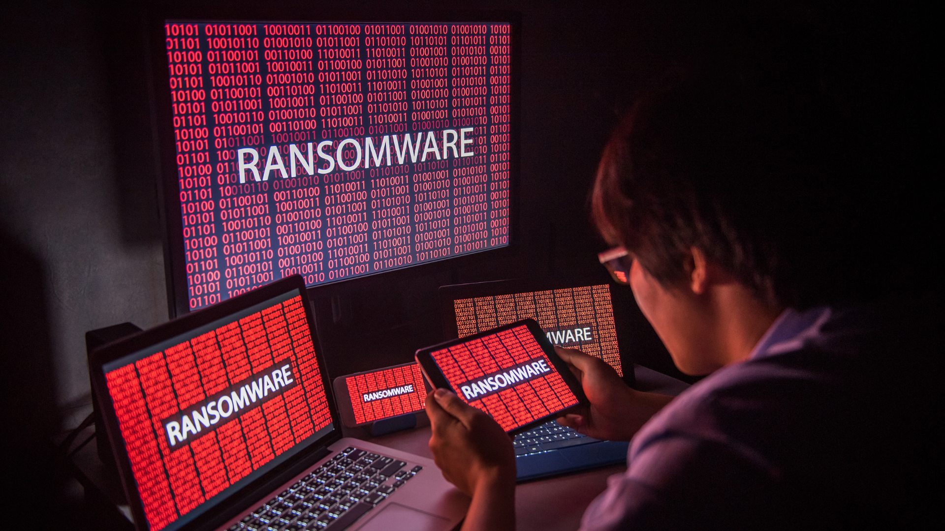 Person stares at devices infected by malware, wondering how to prevent ransomware next time