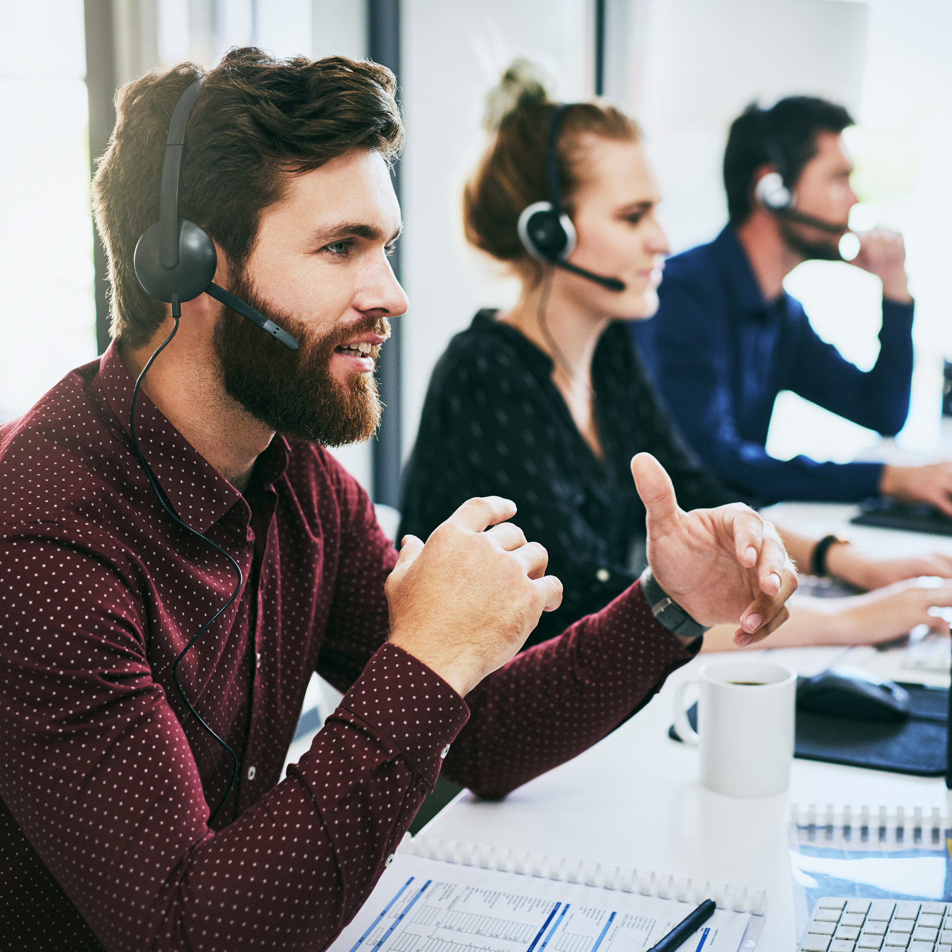 A man with a beard is wearing a headset and giving a thumbs up.