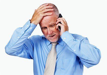 A man in a blue shirt and tie is talking on a cell phone.