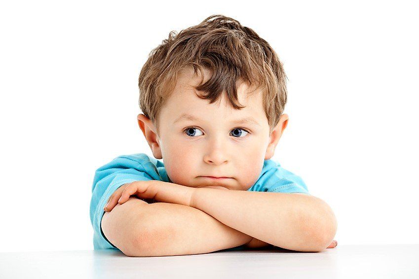 A young boy is sitting at a table with his arms crossed.