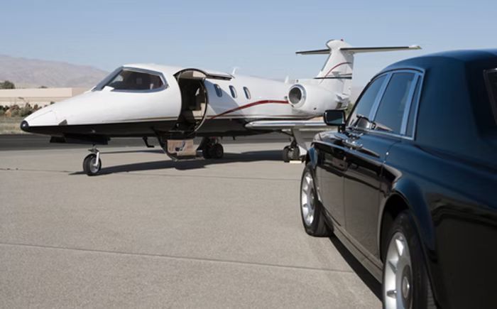 A limousine is parked next to a private jet