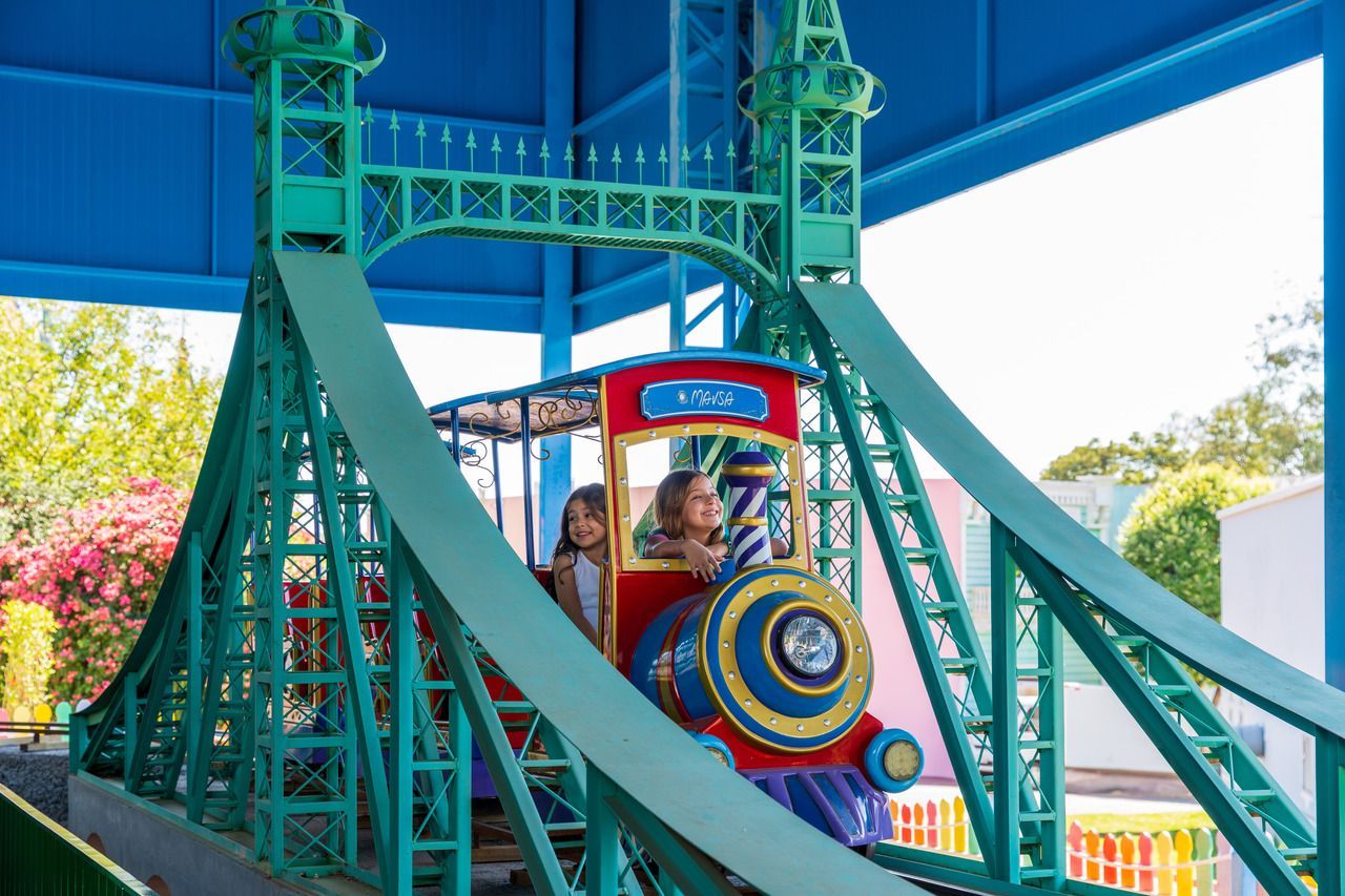 Um playground com uma linha de trem passando por ele e um telhado azul.