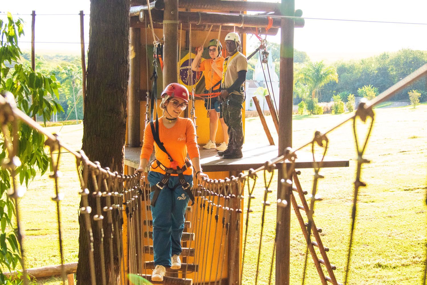Um grupo de pessoas atravessa uma ponte de corda.