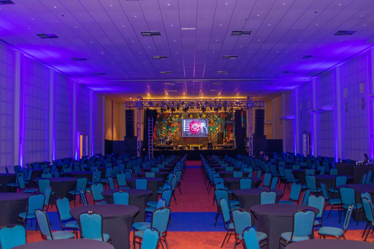 Uma grande sala cheia de mesas e cadeiras e luzes roxas.