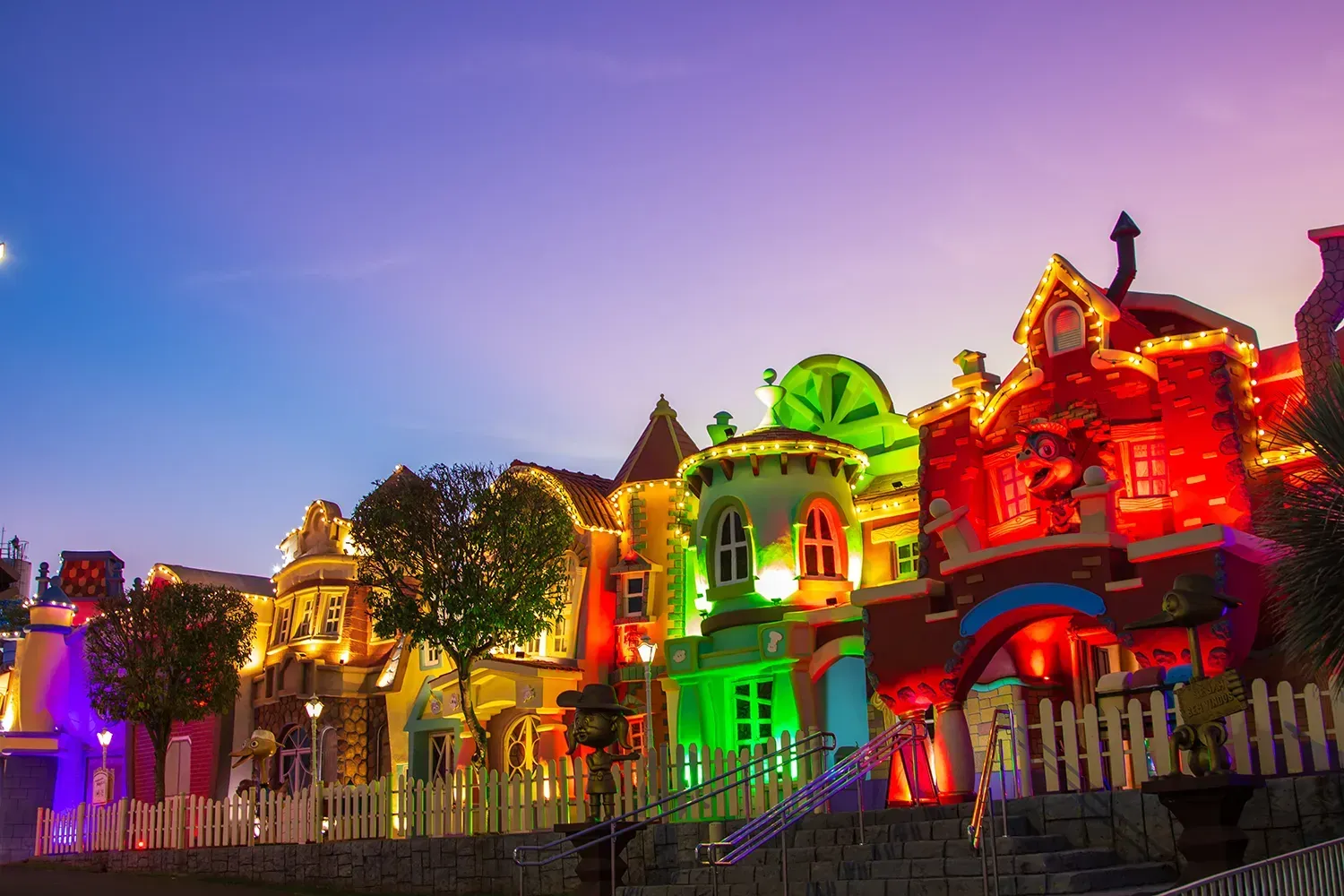 Uma fileira de prédios coloridos fica iluminada à noite.